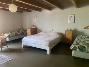 a bedroom with two beds and a chair in it at Belmont-chambres 