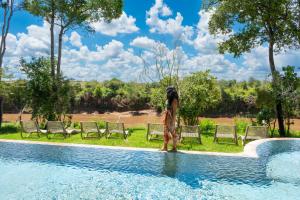 a woman standing next to a swimming pool at Surana Mara Camp in Mara Simba