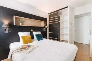 a bedroom with a white bed and a black wall at Apparthotel Le Hüb Grenoble in Grenoble +94 photos