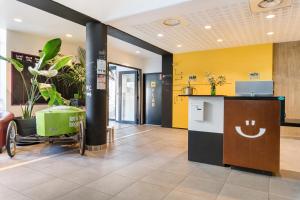 an office lobby with yellow walls and a counter at Apparthotel Le Hüb Grenoble in Grenoble