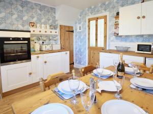 a kitchen with a wooden table with plates and wine glasses at Ferndene Cottage in Hinderwell