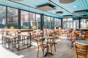 a restaurant with tables and chairs and windows at Apparthotel Le Hüb Grenoble in Grenoble
