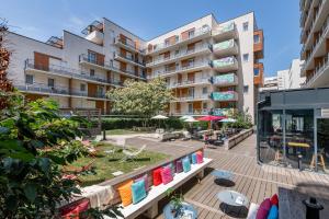 an apartment building with a patio with chairs and umbrellas at Apparthotel Le Hüb Grenoble in Grenoble