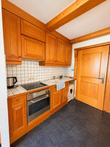 a kitchen with wooden cabinets and a stove top oven at Haus am Anger Top 42 in Königsleiten