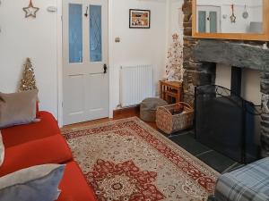 a living room with a fireplace and a red couch at 1 Tower Cottage in Portinscale