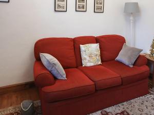 a red couch with pillows on it in a living room at 1 Tower Cottage in Portinscale