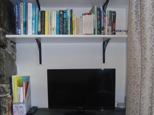 a tv sitting on a shelf with books at 1 Tower Cottage in Portinscale