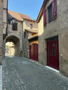 an alley with red doors in a stone building at Petite maison avec cour fermée in Beaulieu-sur-Dordogne
