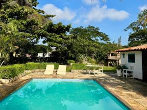 a pool with two chairs and a table in a yard at Peixe Crew Manguinhos in Búzios