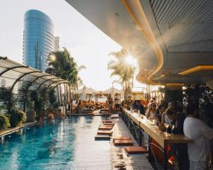 a pool at a resort with people sitting at tables at The George Tel Aviv in Tel Aviv