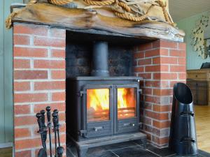 a brick fireplace with a fire in it at Driftwood in Mainsriddle +31 photos