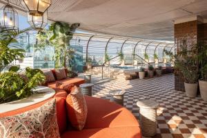 a conservatory with orange furniture and plants in a building at The George Tel Aviv in Tel Aviv