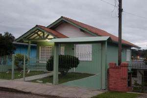 a green house with a fence in front of it at Minha casa em Canela in Canela