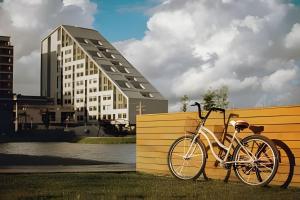 a bike parked against a yellow fence next to a building at Studio 907 Flow Live - Parque Una + garagem in Pelotas