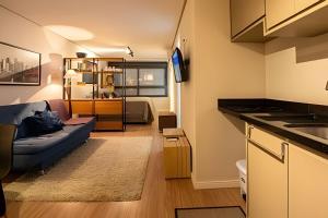 a living room with a blue couch and a kitchen at Studio 907 Flow Live - Parque Una + garagem in Pelotas