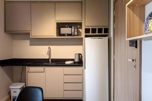 a kitchen with a refrigerator and a microwave at Studio 907 Flow Live - Parque Una + garagem in Pelotas +18 photos