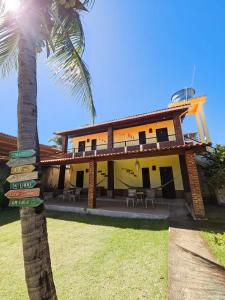 a house with a palm tree in front of it at Aloha Beach Guest House in Maragogi