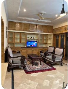 a living room with two chairs and a tv at 4Bdr Spacious Hill View Central E 11 TV Netflix in Islamabad