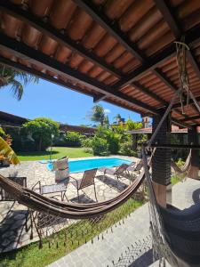 a hammock on a patio next to a pool at Aloha Beach Guest House in Maragogi