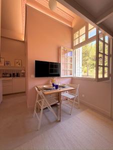 a dining room with a table and a tv at La Boîte Rose - Studio plage de l'Almanarre in Hyères