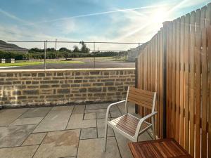 a wooden chair sitting on a patio next to a wall at The Cider Shed -Uk47420 in Curry Mallet