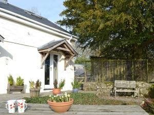 a white house with a wooden awning and some plants at Ty Newydd Cottage in Hoel-galed