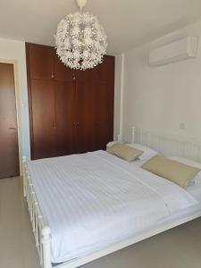 a bedroom with a large white bed with a chandelier at Sun Set at Coral Bay in Peyia +46 photos