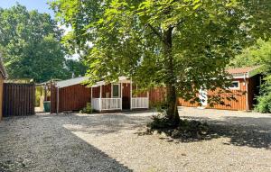 a tree in front of a house with a fence at 2 Bedroom Nice Home In Stenlille in Stenlille