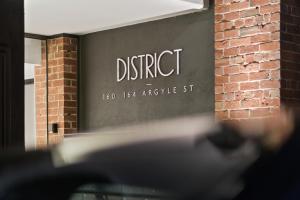 a sign that reads district in front of a building at District Apartments Fitzroy in Melbourne