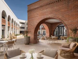 an outdoor patio with tables and chairs and a brick wall at Mercure Conacul Cozieni in Bucharest