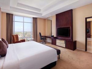 a hotel room with a bed and a flat screen tv at Grand Mercure Solo Baru in Solo