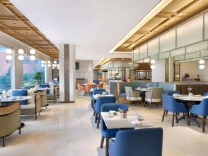 a restaurant with blue chairs and tables and a cafeteria at Grand Mercure Solo Baru in Solo