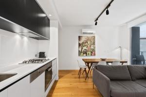 a kitchen and living room with a couch and a table at District Apartments Fitzroy in Melbourne