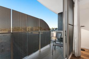 a room with a balcony with a chair and a window at District Apartments Fitzroy in Melbourne