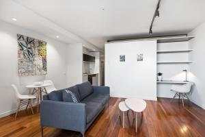 a living room with a blue couch and two tables at District Apartments Fitzroy in Melbourne
