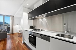 a white kitchen with a sink and a stove at District Apartments Fitzroy in Melbourne