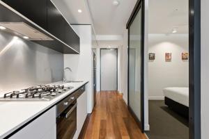 a kitchen with a stove top oven next to a bed at District Apartments Fitzroy in Melbourne