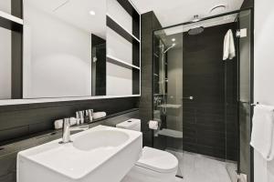 a bathroom with a sink and a toilet and a mirror at District Apartments Fitzroy in Melbourne