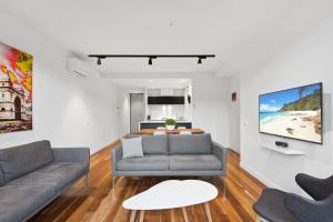 a living room with a couch and a tv on a wall at District Apartments Fitzroy in Melbourne