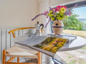 a table with a newspaper and a vase with flowers on it at The Granary - Uk50401 in Llanstephan