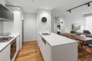 a kitchen and living room with white counters and a table at District Apartments Fitzroy in Melbourne