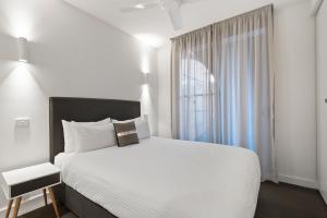 a bedroom with a white bed and a window at District Apartments Fitzroy in Melbourne