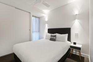 a bedroom with a large white bed and a window at District Apartments Fitzroy in Melbourne