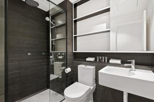 a bathroom with a toilet and a sink and a mirror at District Apartments Fitzroy in Melbourne +27 photos
