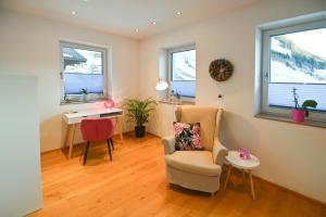 a living room with a chair and a desk and two windows at Chalet Creatina by we rent, NATIONALPARK CARD INCLUDED in Rauris