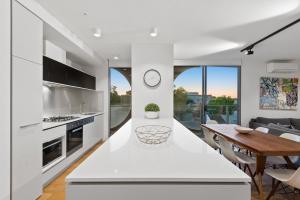 a kitchen and dining room with white counters and a table at District Apartments Fitzroy in Melbourne