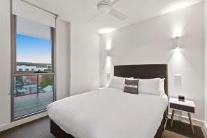 a bedroom with a white bed and a large window at District Apartments Fitzroy in Melbourne