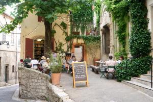 a group of people sitting at tables outside a restaurant at Le Cloître in Arles