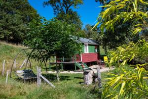 a small red and green house with a playground at Ecrin du Ségala - Roulotte insolite in Tauriac-de-Naucelle