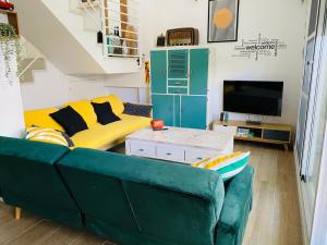 a living room with a green couch and a tv at Marta Beach House - Caños De Meca in Los Caños de Meca